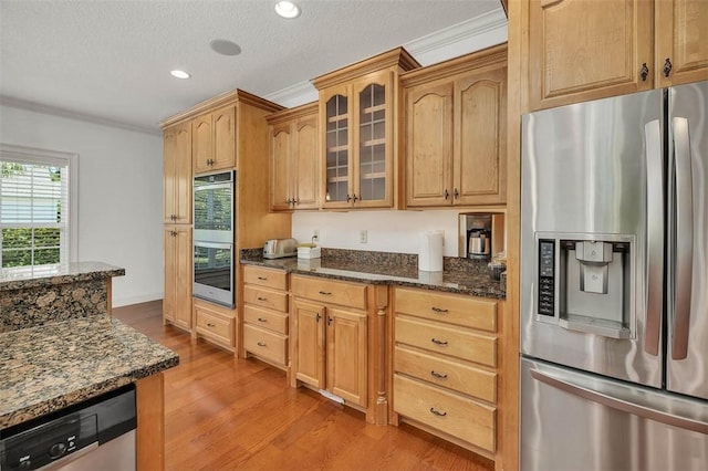 17 Willow Ct, Brunswick, GA 31523 - kitchen featuring appliances with stainless steel finishes, ornamental molding, dark stone counters, light wood finished floors, and glass insert cabinets