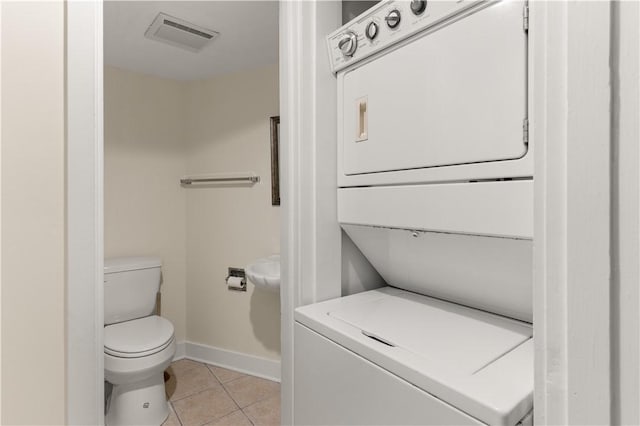 bathroom featuring tile patterned floors, stacked washer / drying machine, and toilet