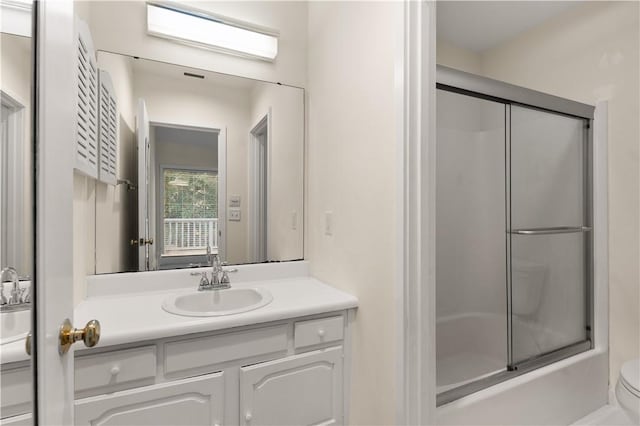 full bathroom featuring combined bath / shower with glass door, vanity, and toilet