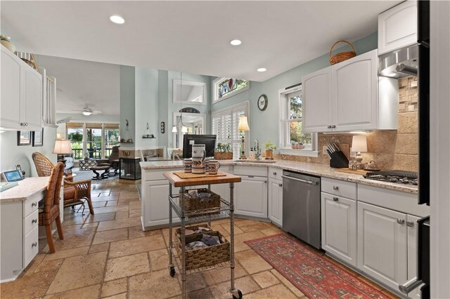 kitchen with backsplash, white cabinets, sink, light stone counters, and kitchen peninsula