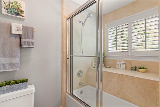 bathroom featuring shower / bath combination with glass door and toilet