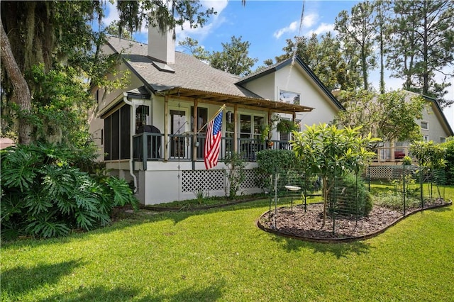 rear view of house with covered porch and a yard