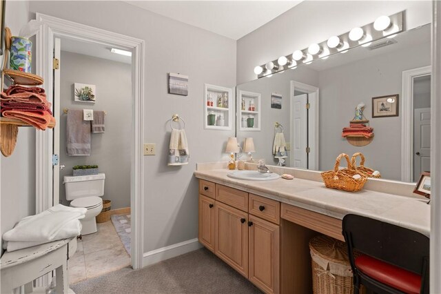 bathroom with toilet, vanity, and tile patterned floors