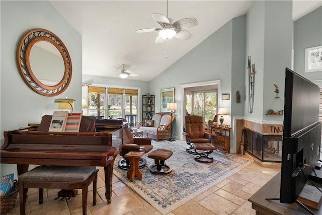 interior space featuring a tiled fireplace, high vaulted ceiling, plenty of natural light, and ceiling fan