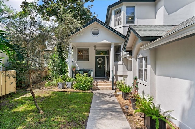 doorway to property featuring roof with shingles, fence, and stucco siding