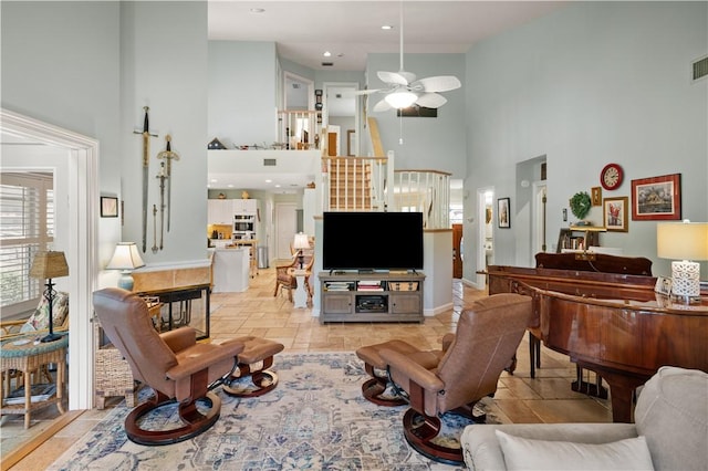 tiled living room featuring ceiling fan and a towering ceiling