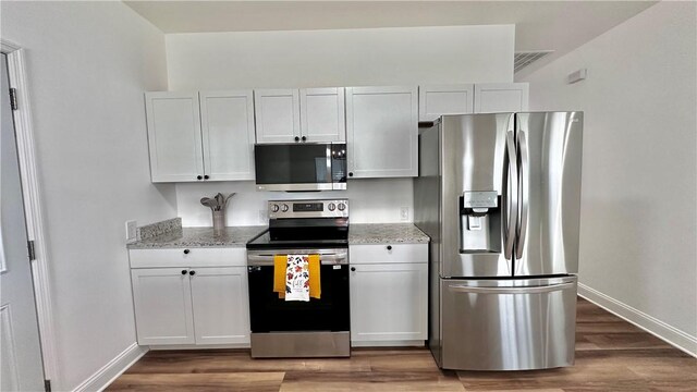 kitchen featuring dark hardwood / wood-style flooring, light stone countertops, white cabinetry, and appliances with stainless steel finishes