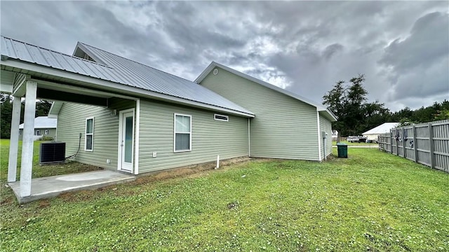 rear view of house with central AC unit and a yard