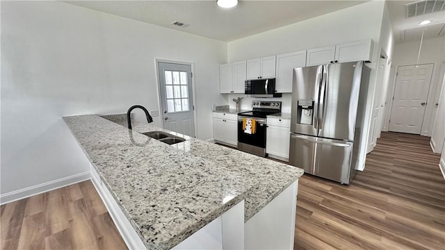 kitchen with sink, white cabinets, light wood-type flooring, and appliances with stainless steel finishes