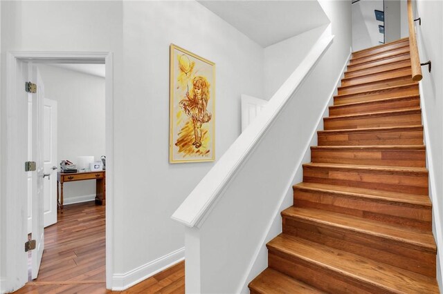 stairway with baseboards and wood finished floors