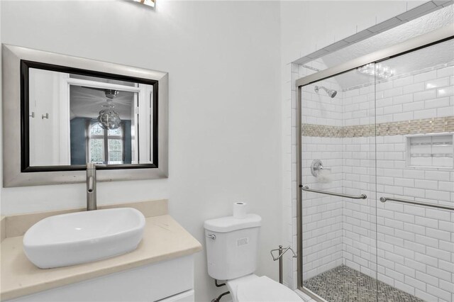 full bathroom with toilet, a stall shower, and vanity