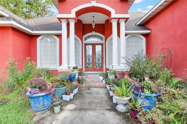 doorway to property with french doors, a shingled roof, and stucco siding