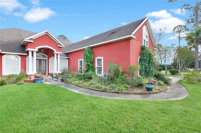 view of front of property featuring a shingled roof, a front yard, french doors, and stucco siding