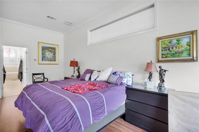 bedroom featuring ornamental molding, wood finished floors, and visible vents