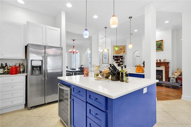 kitchen with light tile patterned flooring, blue cabinets, beverage cooler, white cabinets, and stainless steel fridge