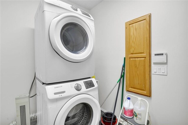 clothes washing area featuring cabinet space and stacked washer / dryer