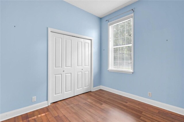 unfurnished bedroom featuring a closet, wood finished floors, and baseboards