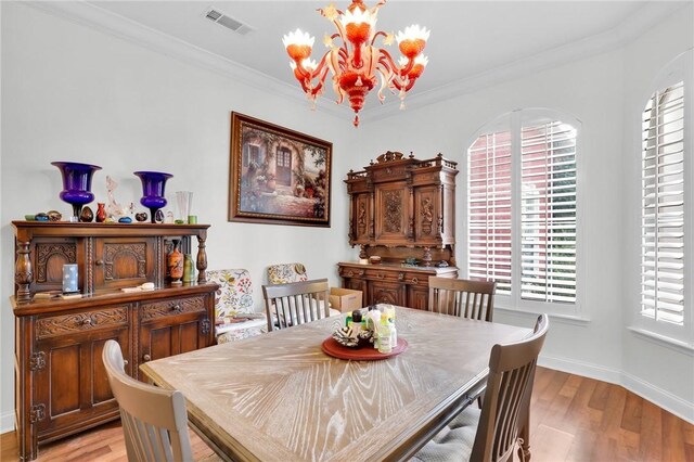 dining area with light wood-style floors, visible vents, and ornamental molding