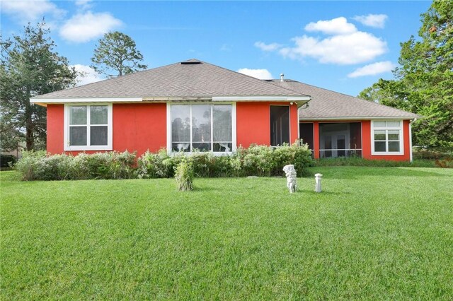 back of property featuring a shingled roof and a yard