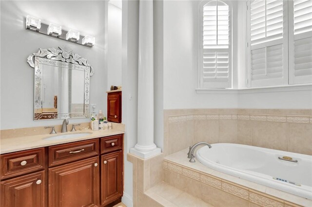 full bathroom with decorative columns, a bath, and vanity