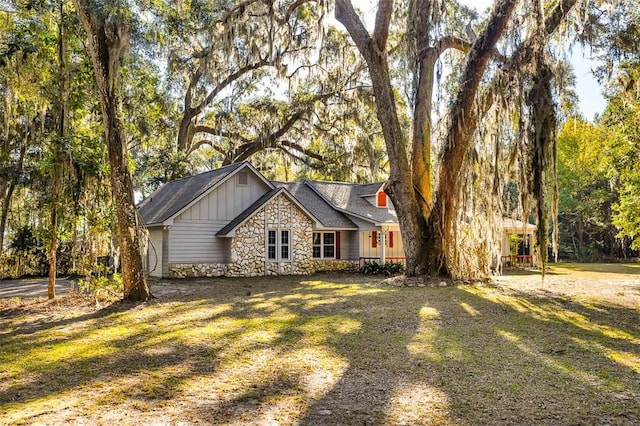 view of front of property with stone siding, board and batten siding, and a front yard