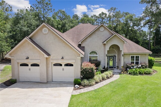 40 Jada Ln, Brunswick, GA 31523 - view of front of home with concrete driveway, an attached garage, stucco siding, a front lawn, and a shingled roof