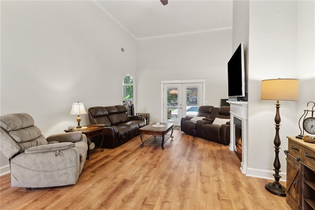 40 Jada Ln, Brunswick, GA 31523 - living room with french doors, crown molding, light wood-style flooring, a warm lit fireplace, and a high ceiling