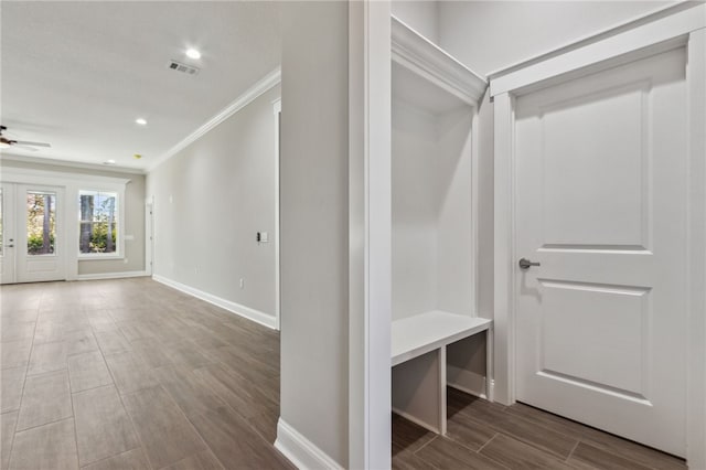 interior space with visible vents, wood finish floors, baseboards, ornamental molding, and a ceiling fan