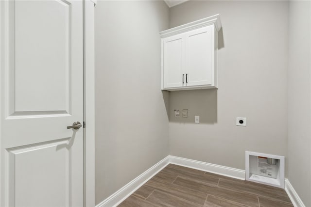 washroom featuring baseboards, wood finish floors, hookup for a washing machine, cabinet space, and electric dryer hookup