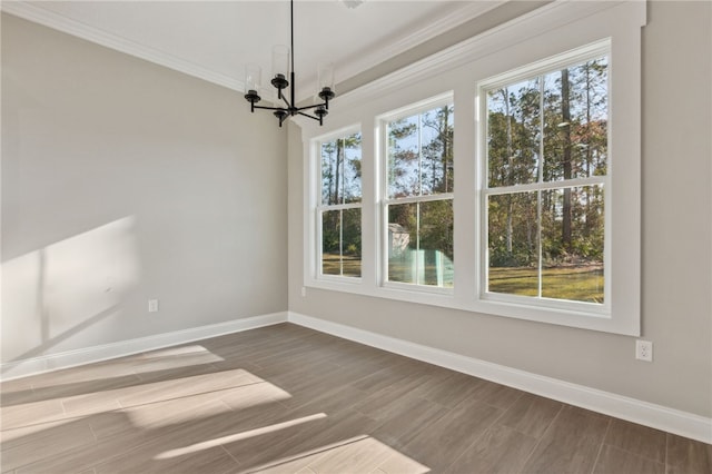 unfurnished dining area featuring a chandelier, wood finish floors, crown molding, and baseboards