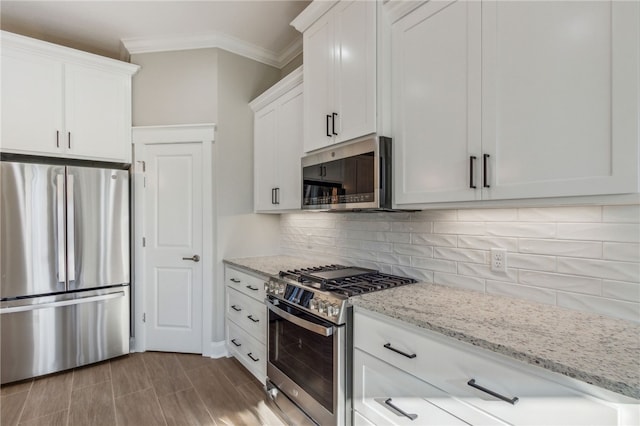 kitchen featuring light stone counters, appliances with stainless steel finishes, white cabinetry, crown molding, and backsplash