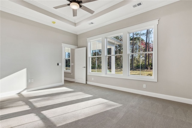 empty room featuring visible vents, plenty of natural light, a tray ceiling, and ornamental molding