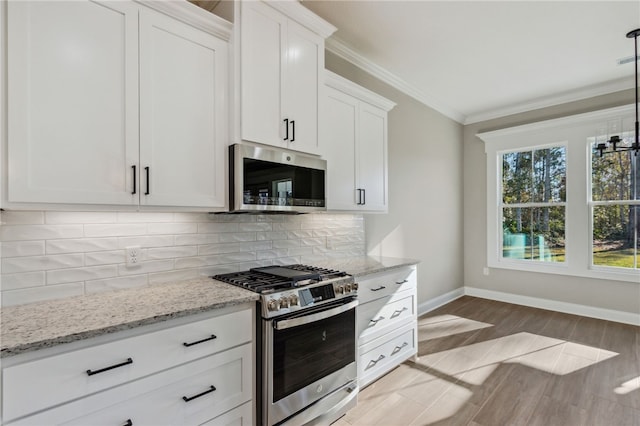 kitchen with tasteful backsplash, ornamental molding, light stone counters, white cabinets, and stainless steel appliances