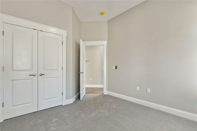 unfurnished bedroom featuring light colored carpet, baseboards, and a closet