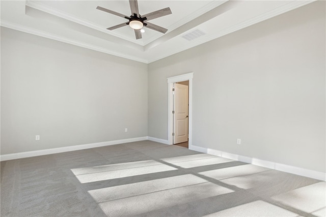 spare room featuring a tray ceiling, carpet, visible vents, and ceiling fan