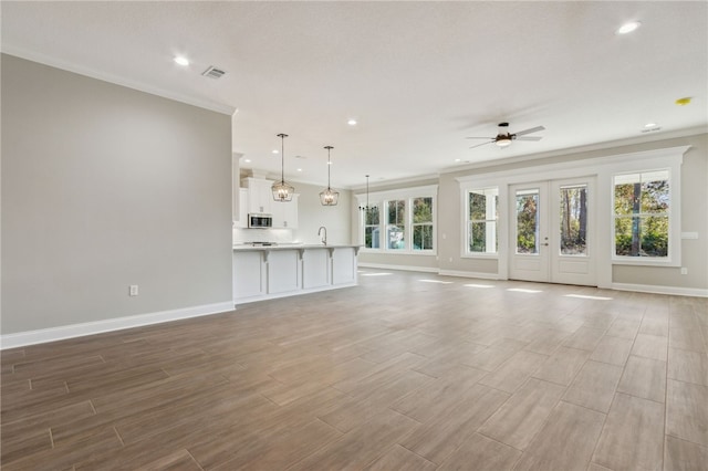 unfurnished living room with baseboards, a ceiling fan, visible vents, and wood tiled floor