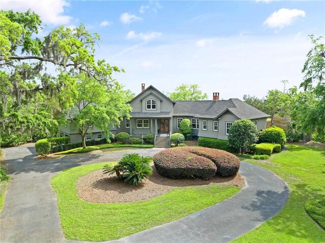 view of front facade featuring a chimney and curved driveway
