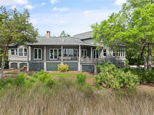 rear view of property with stairs, a shingled roof, and a chimney