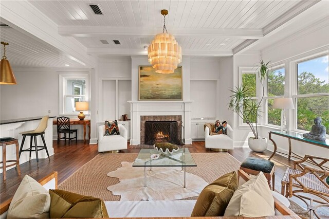 living room with beamed ceiling, wood finished floors, crown molding, and a lit fireplace