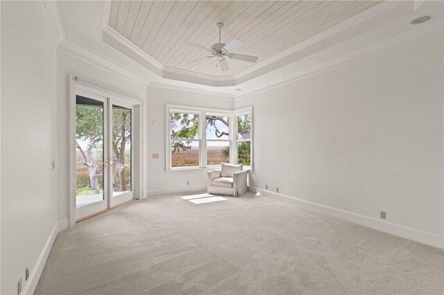 unfurnished room with ceiling fan, carpet, wooden ceiling, ornamental molding, and a raised ceiling