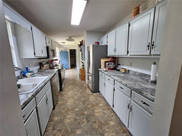 300 Crestview Dr, Woodbine, GA 31569 - kitchen with stainless steel appliances, a sink, tasteful backsplash, a textured ceiling, and stone finish floors