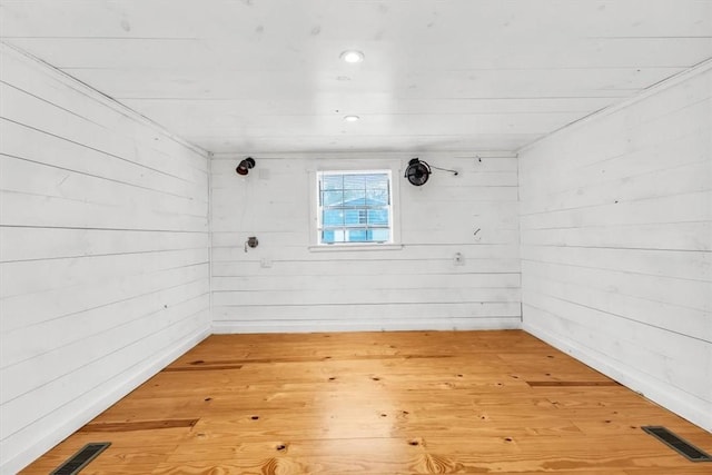 spare room featuring wooden walls, visible vents, and wood finished floors