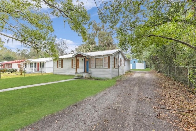 view of front of home with a front lawn, fence, and dirt driveway