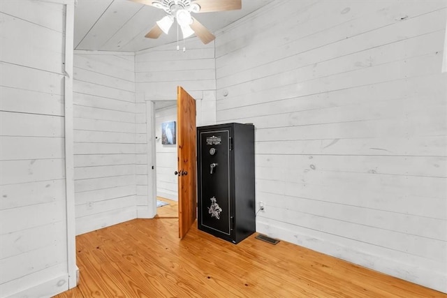 interior space featuring ceiling fan, wooden walls, visible vents, and wood finished floors
