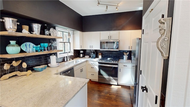 kitchen featuring light stone counters, stainless steel appliances, backsplash, white cabinets, and a sink