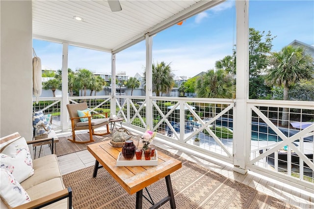 sunroom / solarium with a ceiling fan and a water view