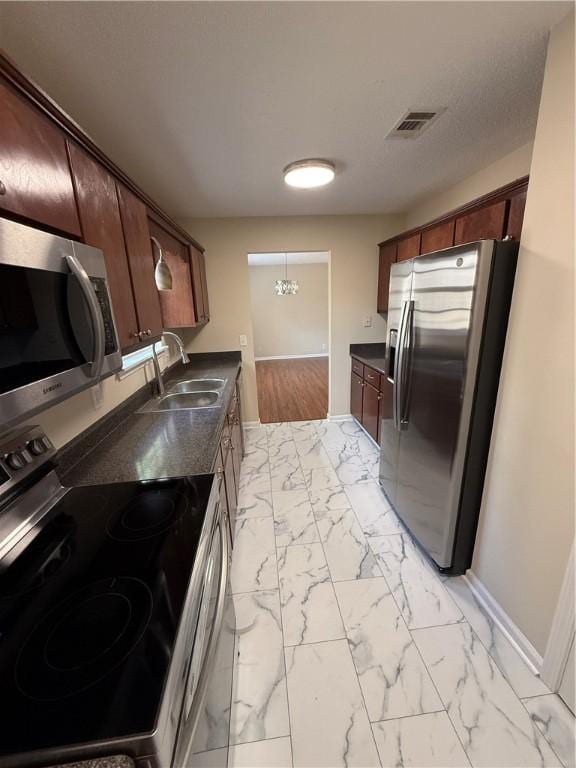 kitchen with appliances with stainless steel finishes, sink, and a notable chandelier