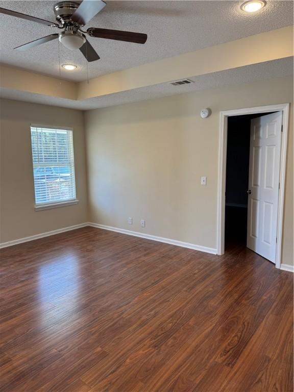 spare room featuring ceiling fan, dark wood-type flooring, and a textured ceiling