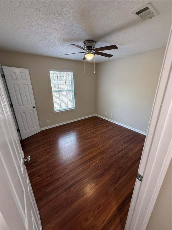 spare room with ceiling fan, dark hardwood / wood-style floors, and a textured ceiling