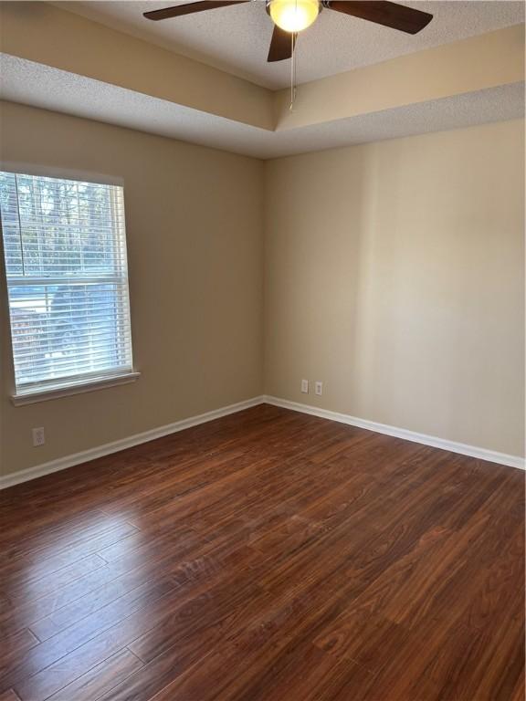 spare room with dark wood-type flooring, ceiling fan, and a textured ceiling